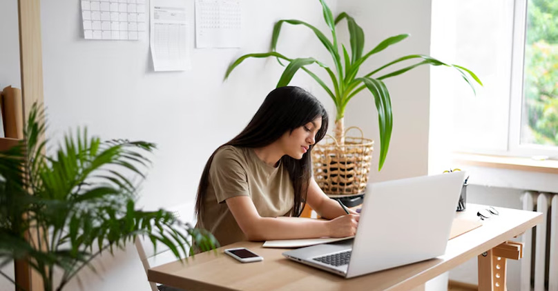 menina escrevendo anotações na frente de um notebook